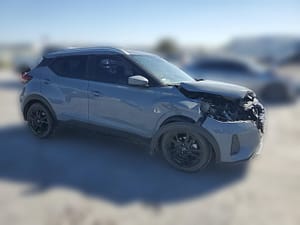 Gray 2023 Nissan Kicks SV crossover with heavy front-end collision damage at a salvage auction